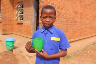 Child holding mug of porridge in Malawi