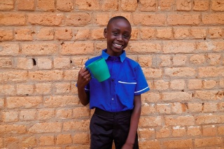 Child in Haiti with mug of Mary's Meals