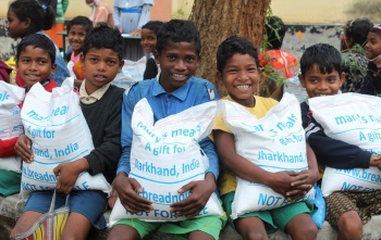Children in India holding bags of take home rations 