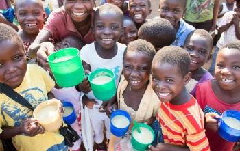 Smiling group of children with mugs of porridge