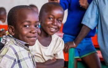 Two children smiling sitting in a classroom