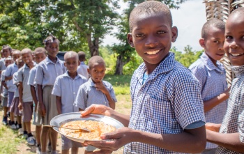 Children queueing and smiling with plates of food