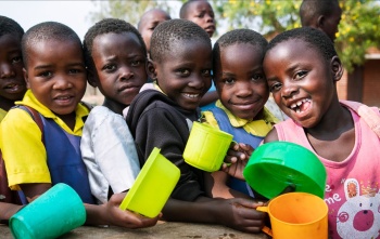 Group of girls holding colourful mugs smiling to camera
