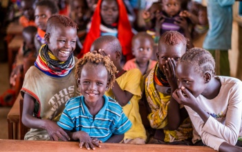 Children in a classroom sitting a table and laughing with each other