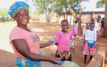 Volunteer in Malawi serving food to children