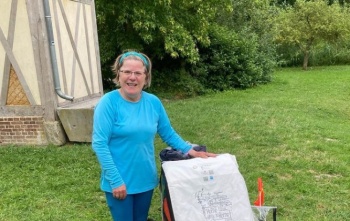 Woman in blue t-shirt standing in campsite with trailer and sign