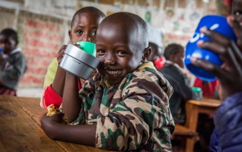 A smiling child poses with a mug in a classroom in Kenya