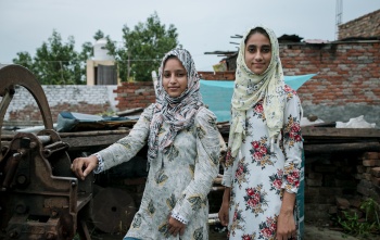 Two young sisters, Fatima and Soni, stand outside in India