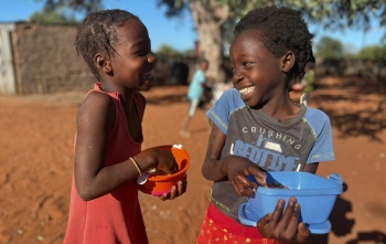 Happy children in Mozambique outside eating Mary's Meals