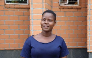 A young woman, Bernadette, stands outside the school she teaches at