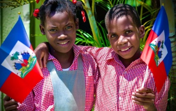 Two smiling children holding the Haiti flag