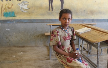A girl sits at a classroom desk in Ethiopia.