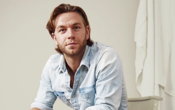 Cropped image of actor Wilf Scolding sitting on a chair