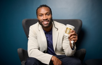 Stuart Douglas sitting on a chair holding a coffee cup and set of keys