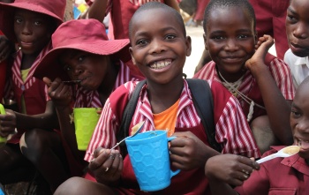 Children smiling while holding Mary's Meals mugs
