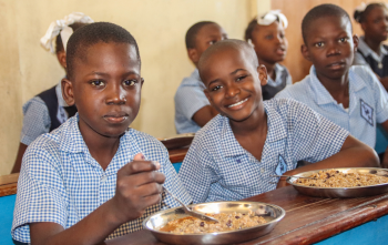 Three boys eating Mary's Meals at school in Haiti