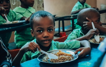 Boys in Haiti classroom eating from a boy