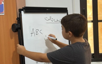 A young boy writes on a white board