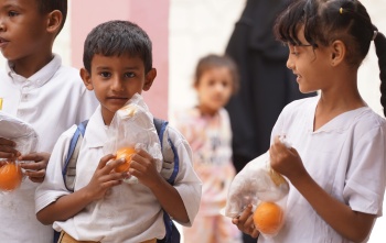Children holding oranges outside