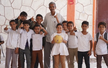 Mr Yasser, a member of school staff, stands with happy children