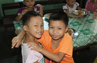 two young boys hugging and looking happy while smiling at the camera 
