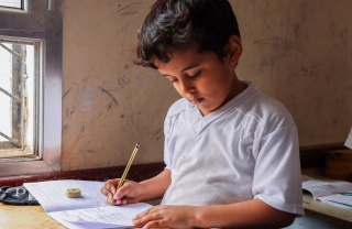 Young boy reading from a school book