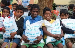 Children in India holding bags of take home rations 