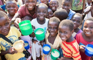 Smiling group of children with mugs of porridge