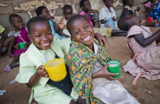 children smiling with mug of porridge