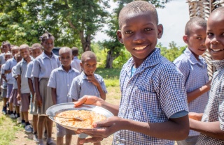 Children queueing and smiling with plates of food