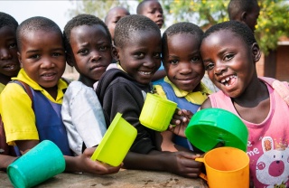 Group of girls holding colourful mugs smiling to camera