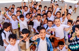 Happy, smiling children wave at camera in school