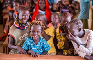 Children in a classroom sitting a table and laughing with each other