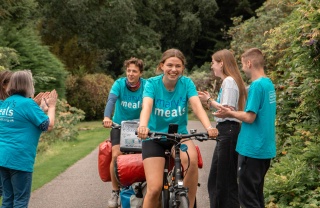 Jacob and Lucia cycling and being cheered on by supporters