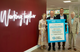 4 people stand in front of cheque presented to Mary's Meals charity by Insights