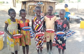 Smiling school children holding plates of maize and beans