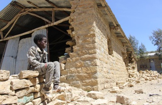 Child sitting outside a destroyed school