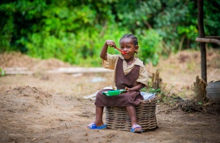 A girl sitting outside eating Mary's Meals in Liberia