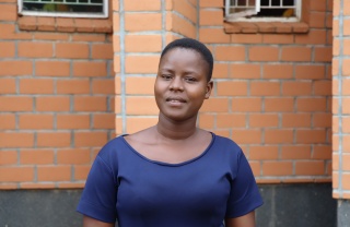 A young woman, Bernadette, stands outside the school she teaches at