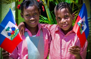Two smiling children holding the Haiti flag