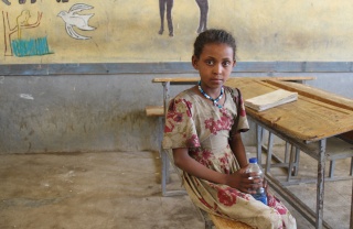 A girl sits at a classroom desk in Ethiopia.