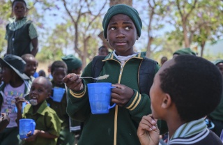 A child at Zhakata School eats his Mary's Meals porridge with a spoon.