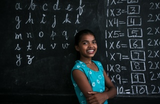 An image of a child in India in front of a chalkboard