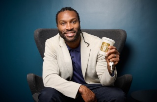 Stuart Douglas sitting on a chair holding a coffee cup and set of keys