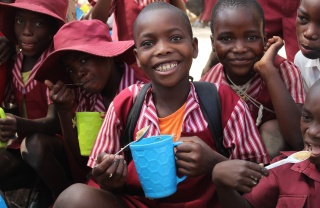Children smiling while holding Mary's Meals mugs