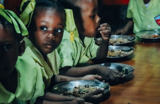 Children in Haiti eating meals at a long table