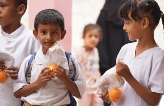 Children holding oranges outside