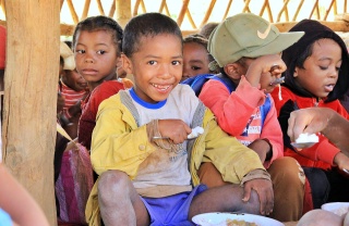 A child eats food from a bowl while smiling