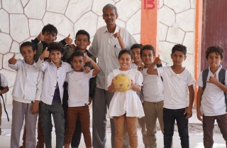 Mr Yasser, a member of school staff, stands with happy children