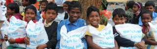 Children in India holding bags of take home rations 